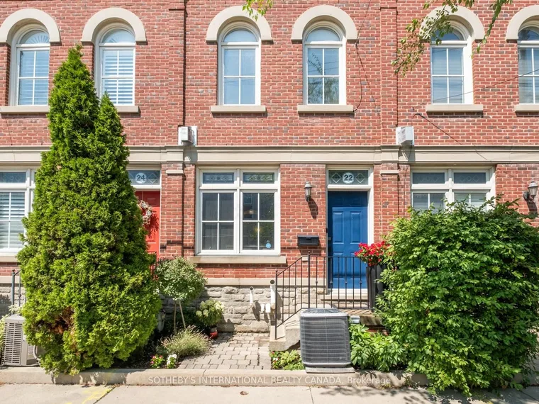 Row of three-storey red-brick townhouses with arched upper windows and a blue front door at 22 St. Raymond Heights, Toronto, Ontario